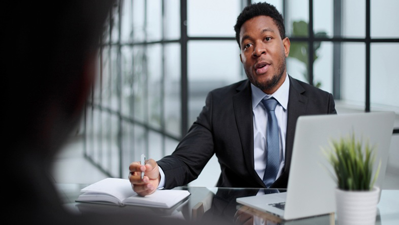 Focused young businessman signing agreement with skilled lawyer